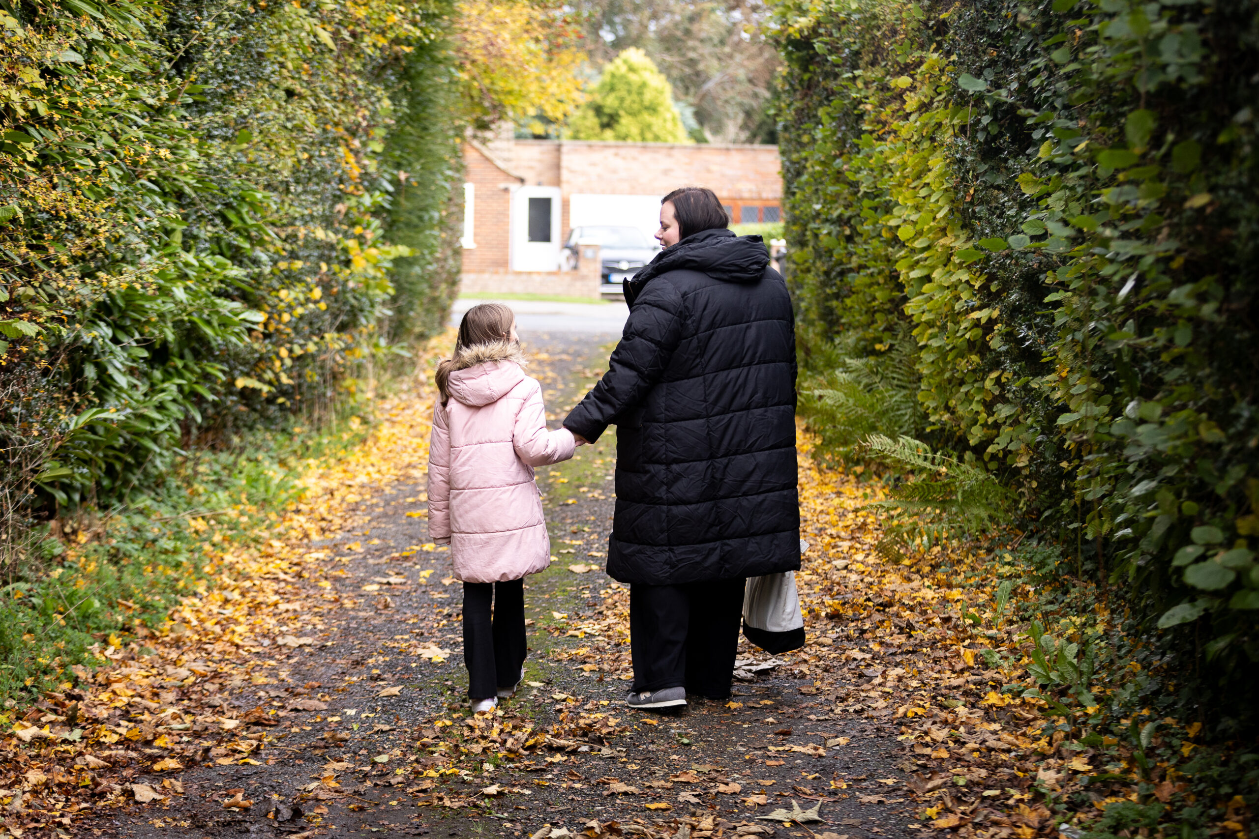 A woman with long, dark brown hair, in a green top, stood outside next to a tree.